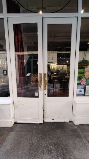 Glass doors with white frames. Pull gold handles in centre to open.