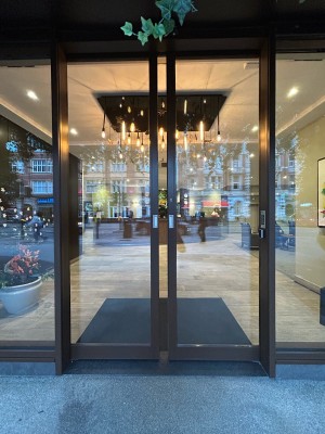 Double sliding automatic glass doors with brown frame.