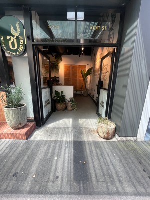 Glass double doors with black metal frame. Push from middle. Ramp ahead to right through doors. Plant pot obstructing on right.