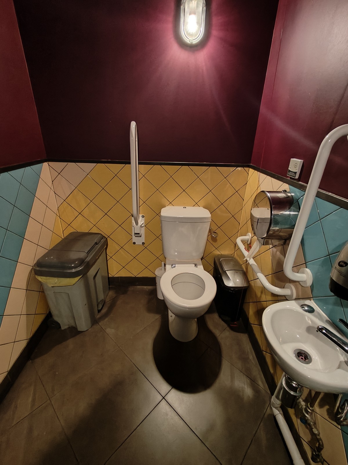 From door facing left. Sink on right wall. Toilet at back right. Pull cord to its right.