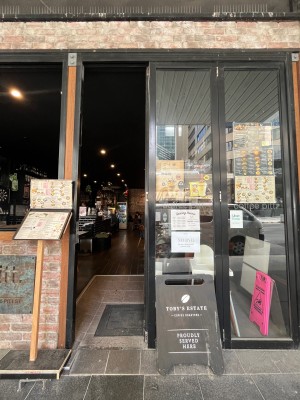 Glass double doors with black metal frame. Push from middle to open. Signage obstructing on right.
