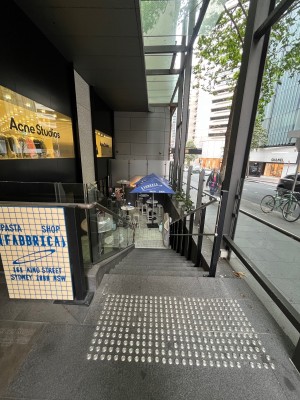 Staircase down to entrance. Black metal handrails either side.