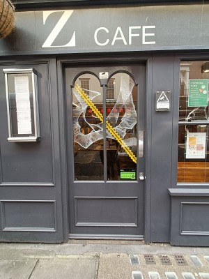 Glass door with grey frame. Silver, metal pad on right. Push to open.
