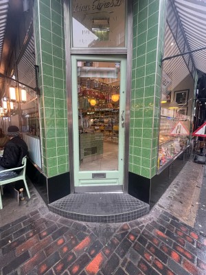 Glass door with green frame ahead. Silver metal handle to right. Push to open.