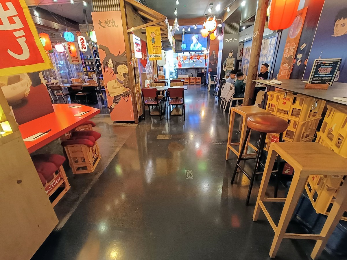 From after tables and stools, looking straight. Tables and stools along left. tables and chairs at back left. High tables and stools along right.
