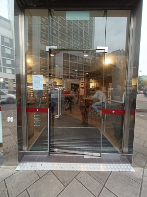 Glass door with silver metal handle on left. Push to open. White doorbell on left.