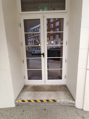 Glass doors with white frame. Black, metal handle on left. Pull down to unlock, pull to open.