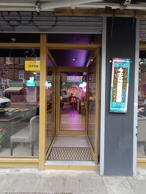 Glass door with golden frame. Golden, metal handle on left. Push to open.