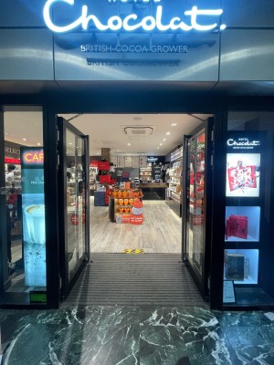 Glass doors with black frame ahead. Silver vertical metal handles in centre. Push to open.