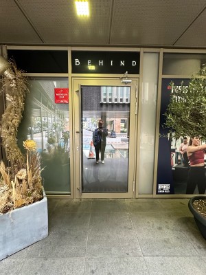 Glass door with green frame ahead. Silver metal vertical handle on left, pull to open.