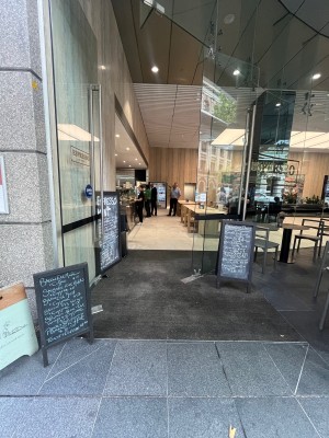 Glass door with silver vertical handle. Push from right.