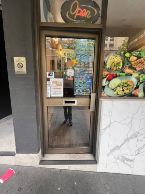 Glass door with brown metal frame. Push from right.