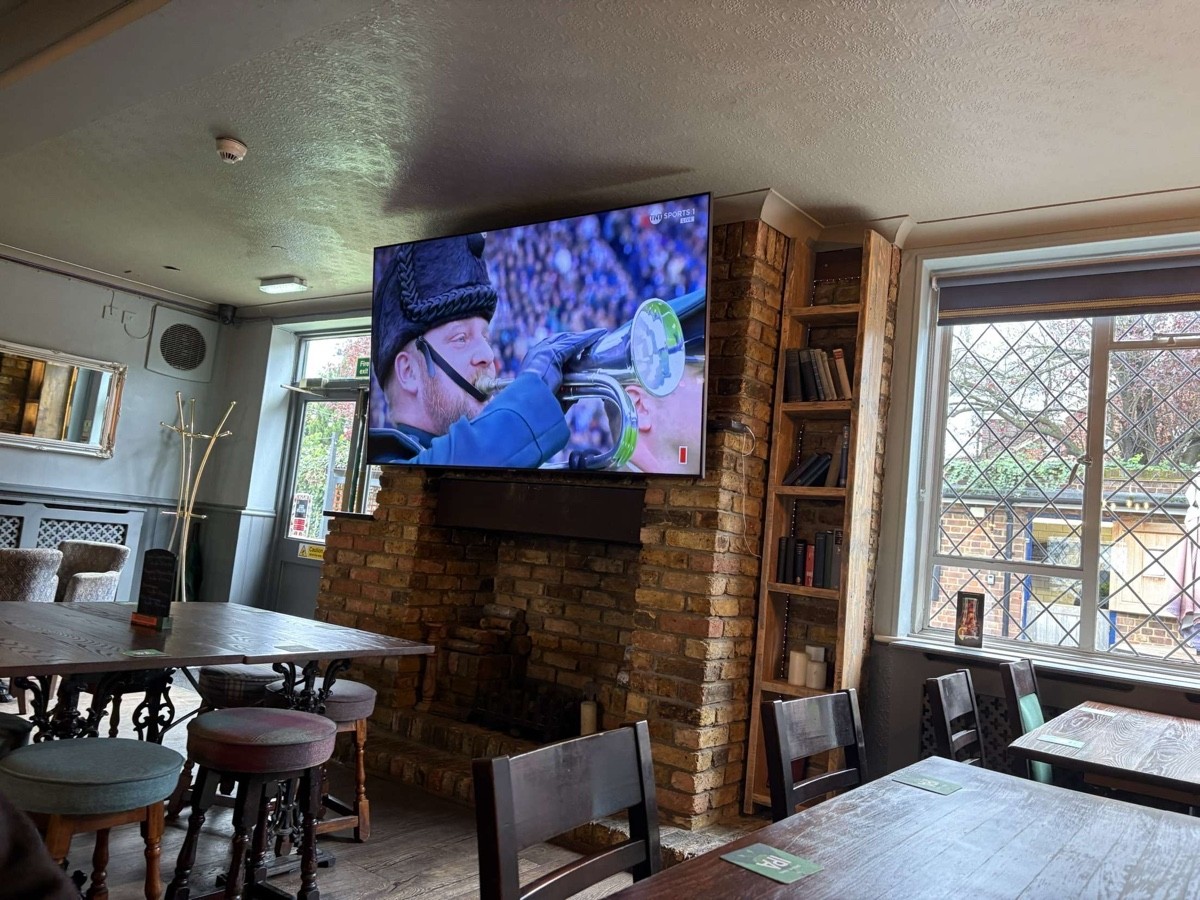 Standard height tables with a mixture of standard chairs and stools for seating. Large tv in area