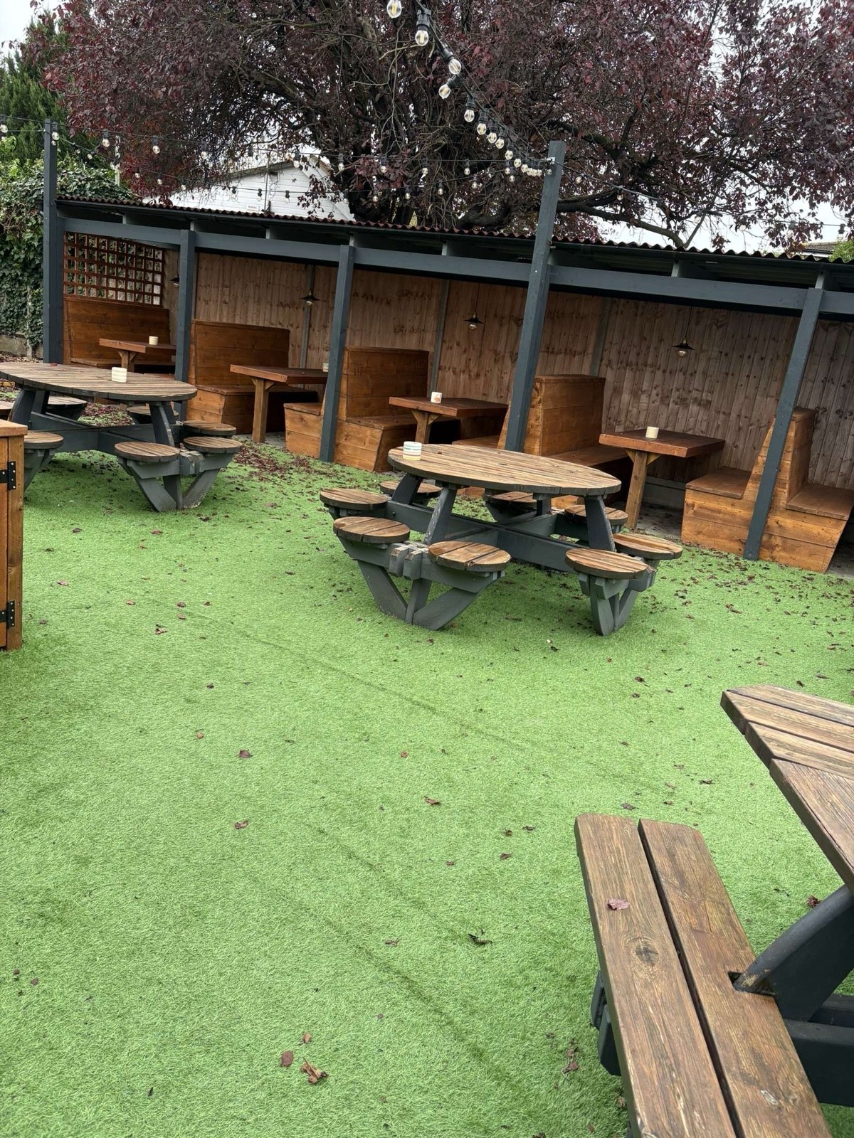 Tables with stools attached and booths that  are covered with standard hight tables. Floor is artificial grass