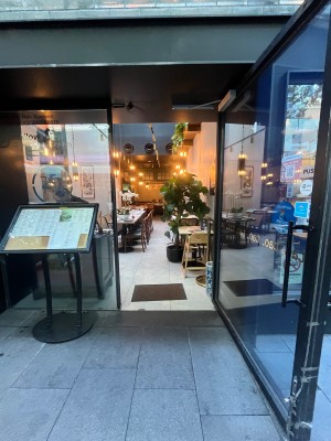 Glass door with black metal frame. Pull black handle from left. Doormat after door.
