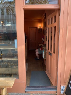 Light orange door with glass panels. Push to open via metal handle on left.