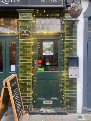 Green door with glass panel ahead. Pull to open via golden handle on left.