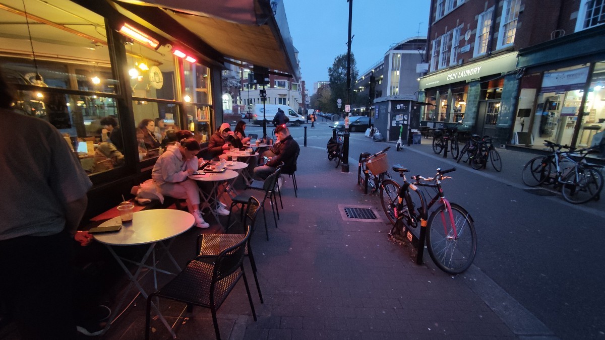 From entrance facing right. Tables with benches and chairs along left wall. Sidewalk to right.