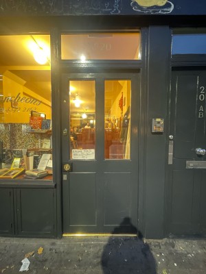 Grey wooden and glass door ahead. Ring button to left. Press button for staff to open door. Door opens inwards.