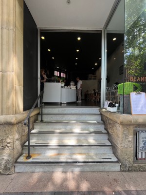 Open archway to venue. 6 steps up through archway. Handrail on left.