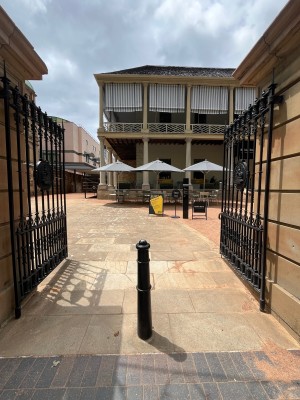 Black metal gates. Push from middle. Central bollard obstructing path ahead.