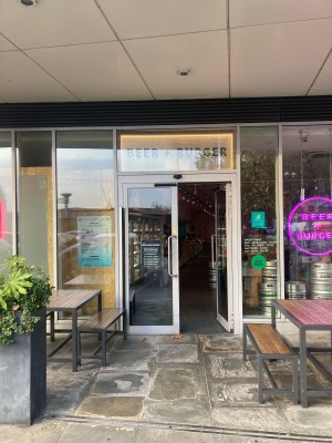 From side street, facing venue. Path ahead to doors on back. Outdoors seating on both sides.