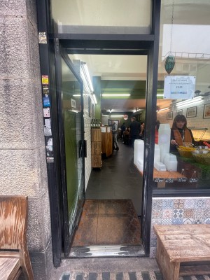 Glass door with black frame ahead. Black metal handle to right. Push to open.