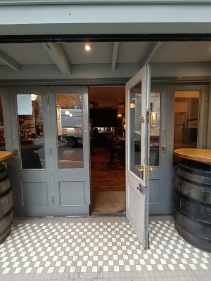 Glass door with grey frame. Pull golden, metal handle on left to open.