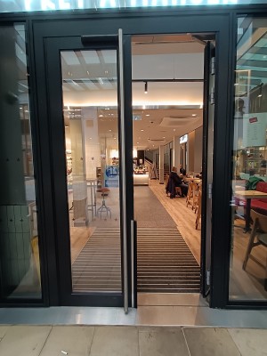 Glass doors with black frame. Push silver, metal handles in middle to open.
