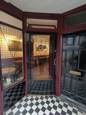 Glass door with black frame. Pull golden, metal handle on right to open.