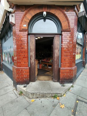 Facing brown-framed glass panelled door. Push golden metal handle on left to open.