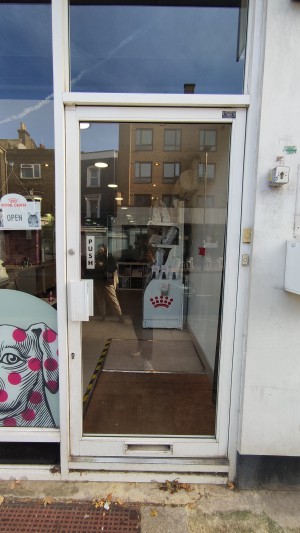 Glass door with white frames. Push white handle on left to open.