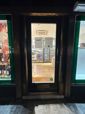 Glass door with black frame. Handle on right, push to open.