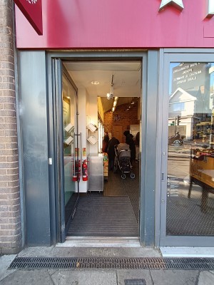 Glass door with with grey frame. Silver, metal handle on right. Push to open.