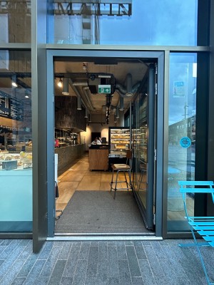 Grey framed glass door with silver handle on left. Push to open.