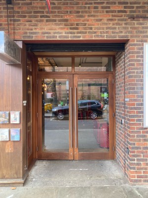 Opening ahead followed by glass doors with wooden frame. Pull metal handles in centre to open.