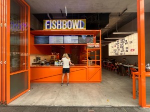 Glass doors with orange metal frame. Doors fold open to left. Doors typically open during business hours.