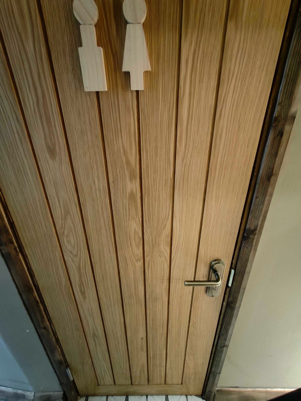 From midway of path, facing right. Wooden door ahead. Pull to open via metal handle on right.