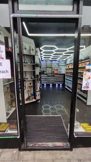 Glass door with black frames. Push black handle on right to open.