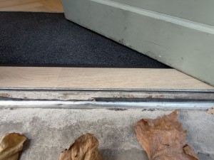Small step on threshold of door followed by doormat after door.