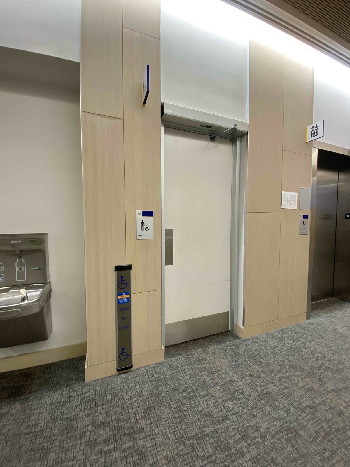 long, low-to-ground push button for automatic door, push door, not obstructed unless people waiting for elevator or coming from stairs opposite door