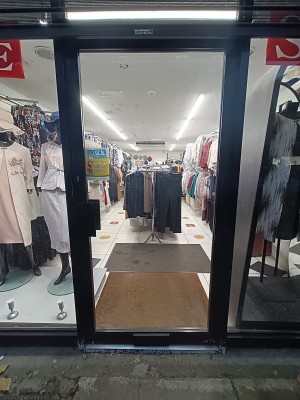Glass door with black frame. Push black, metal handle on left to open.