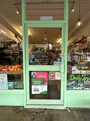 Glass door with green frame. Metal handle on right, push to open.
