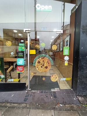 Glass door with silver, metal handle on left. Push to open.