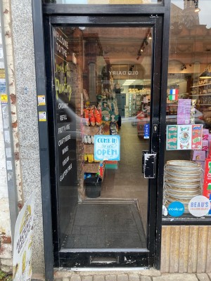 Glass door ahead with black frame. Push to open via metal handle on right.