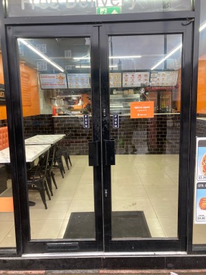 Glass door with black frame ahead. Push to open via handles in center.