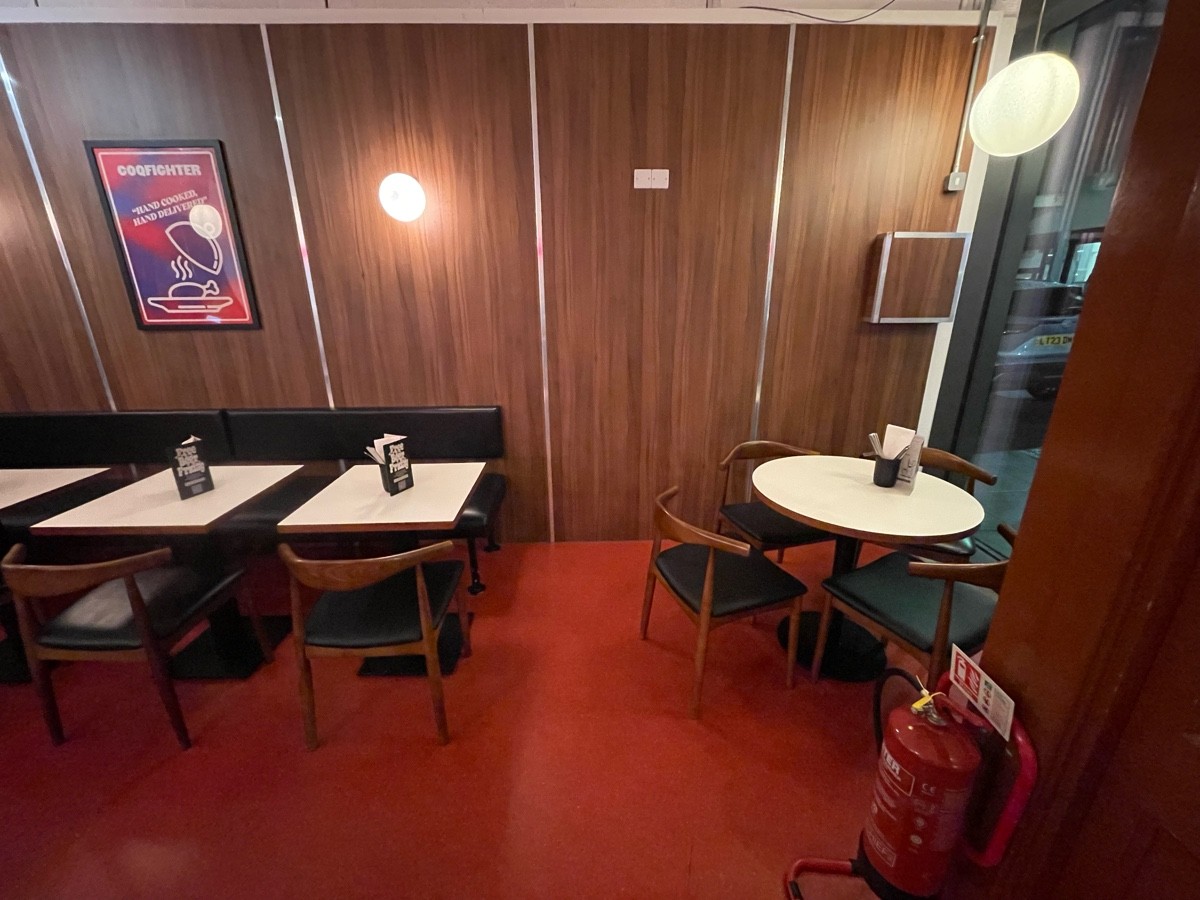 From entrance facing right. Round table ahead on right. Half booths with chairs along left of wall ahead.