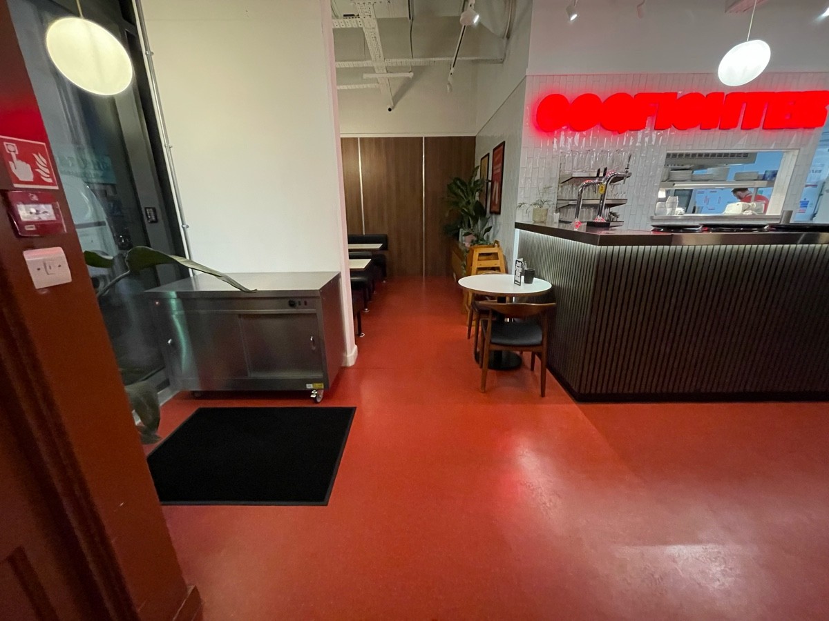 From entrance facing left. Dividing ahead wall on left. Small table with chairs ahead on right. Counter to its right.