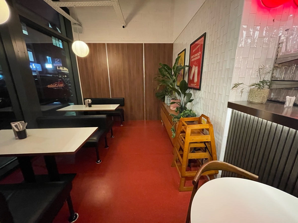 From dividing wall facing right. Two booths ahead on left. Table on immediate right. Baby chairs and shelves behind along back right.