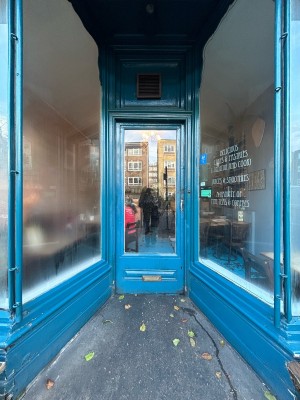 Blue wooden door with large glass panel. Gold handle on right, push to open.
